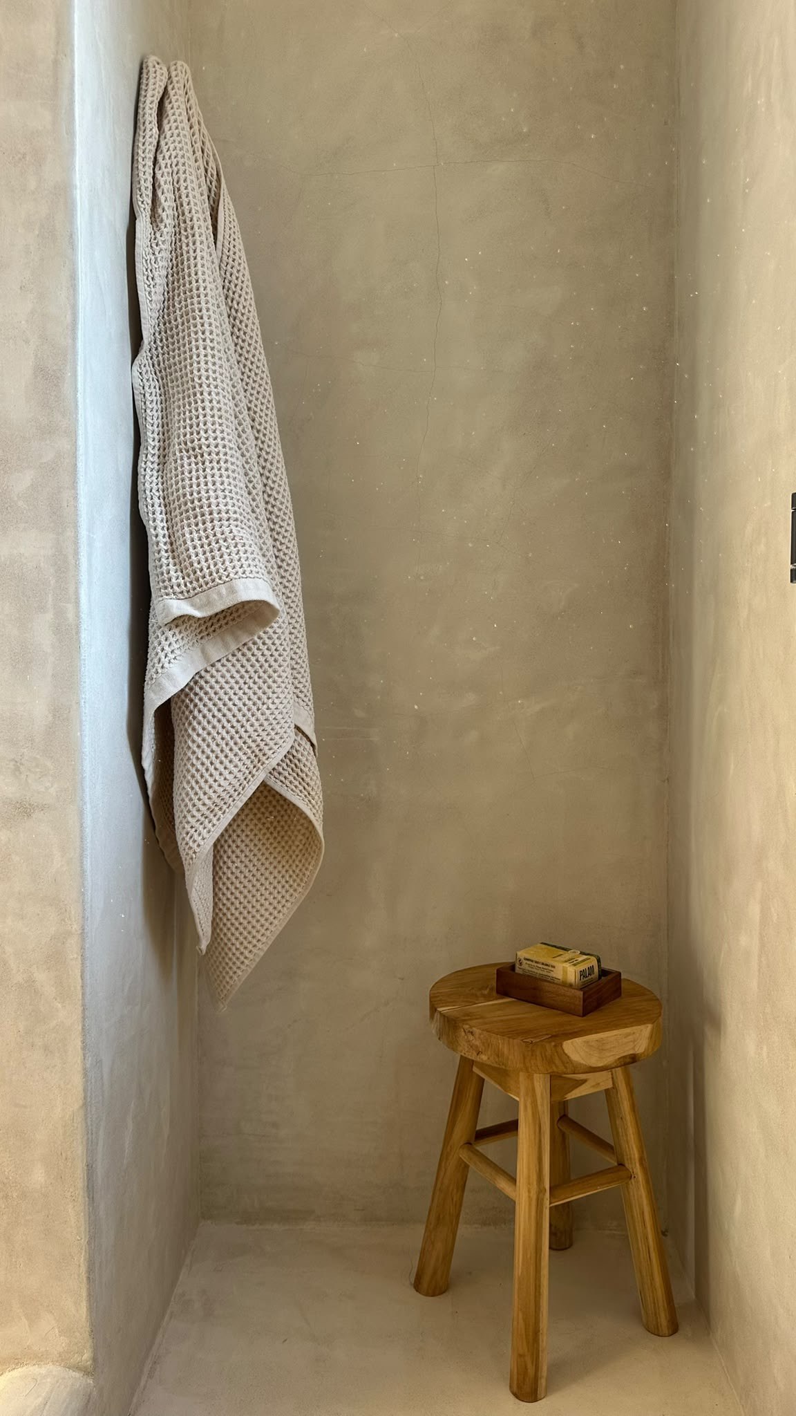 Plaster shower corner with waffle towel and teak stool