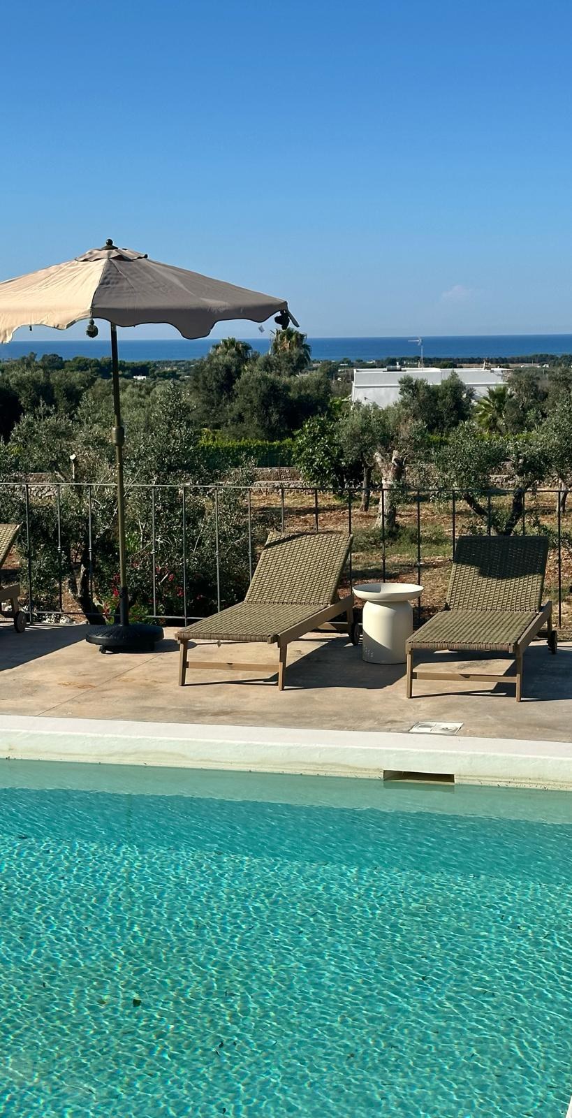 Poolside loungers under an umbrella, the Adriatic beyond