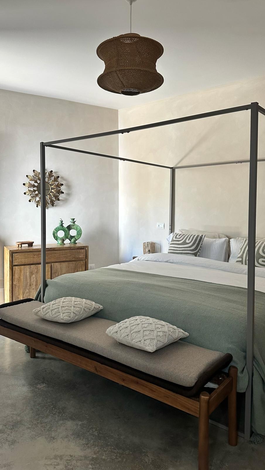 Primary bedroom with canopy bed and green throw